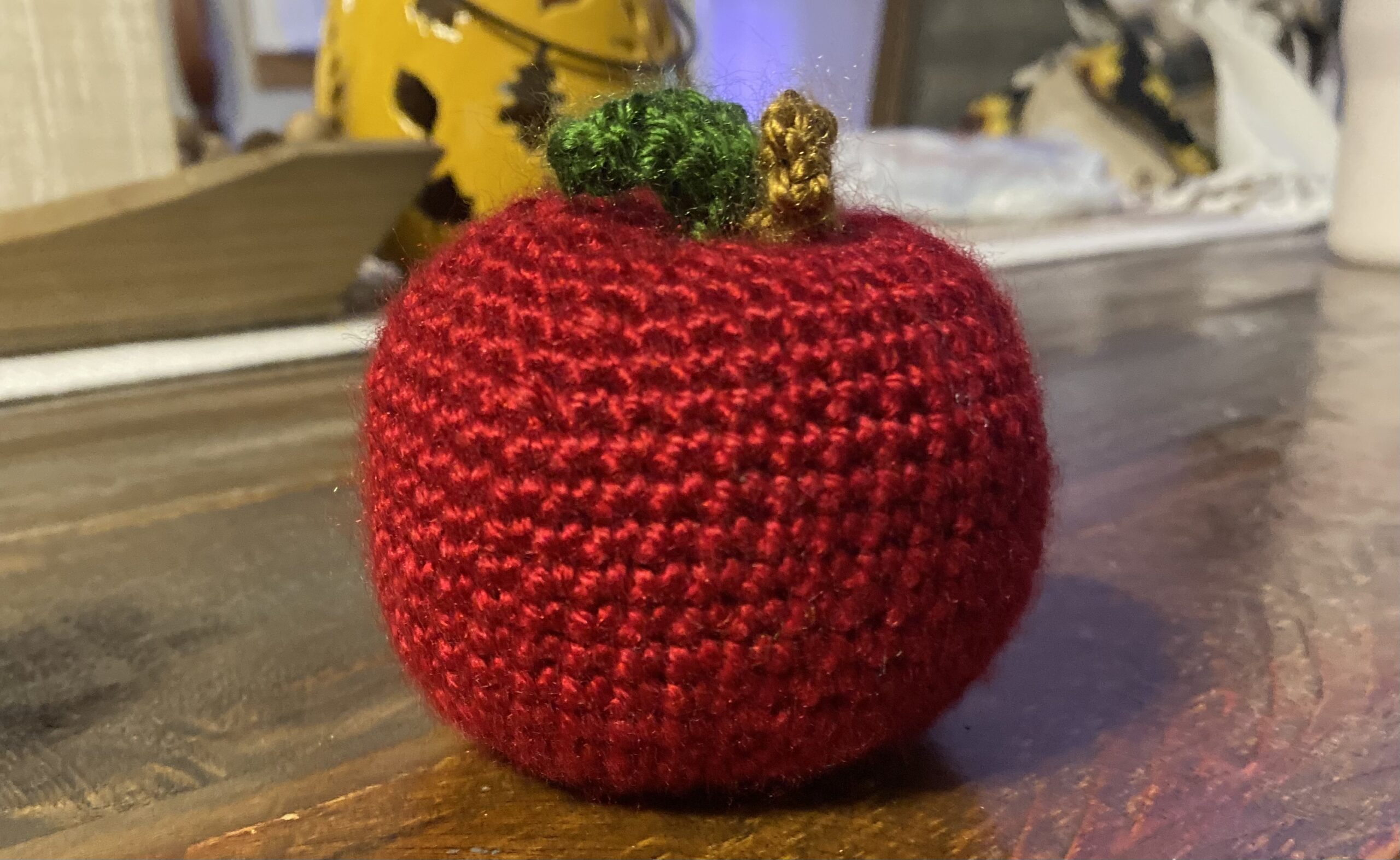 Crocheted stuffed apple sitting on a table